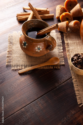 Authentic homemade mexican coffee (cafe de olla) served in traditional handmade clay mug (Jarrito de barro) on rustic wooden table. photo