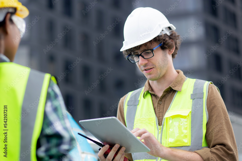 Fototapeta premium Young man and woman is architect planning and inspector project and looking digital tablet at construction site, engineer male and female working and examining for development real estate.