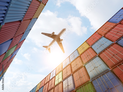 Cargo plane flying above stack of containers at container port photo