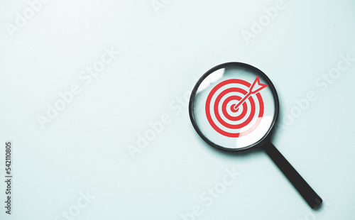 Red dartboard inside of black magnifier glass on blue background for setup objective target and business goal concept. photo