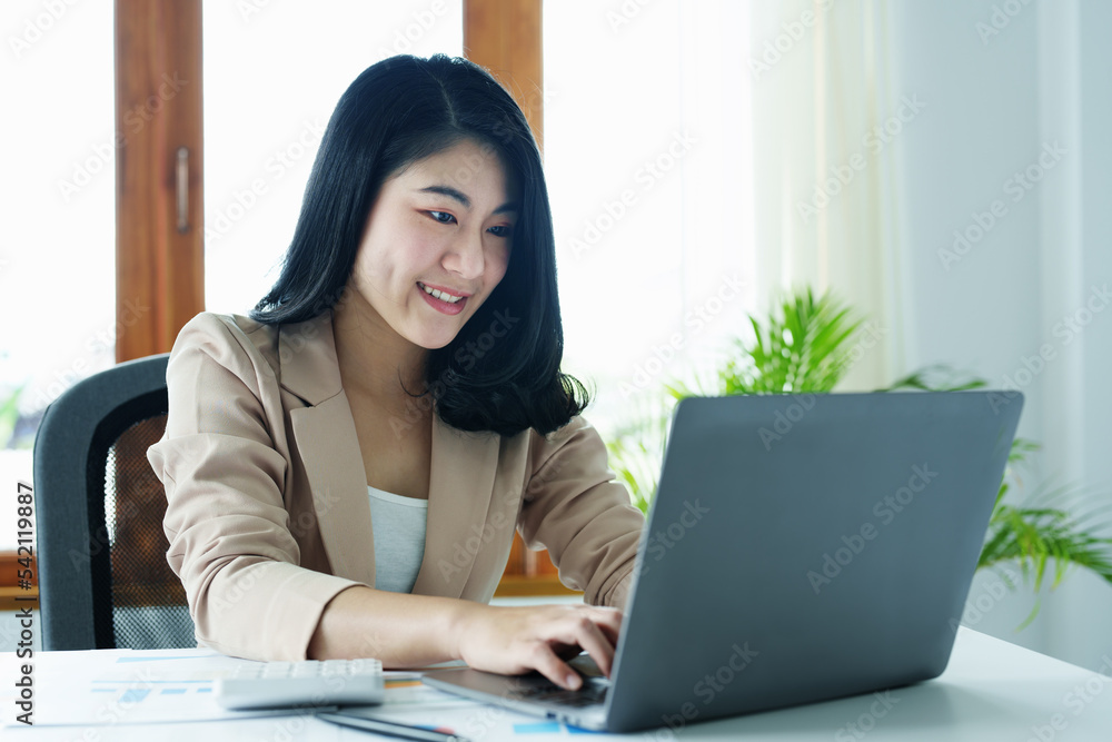 Portrait of a thoughtful Asian businesswoman looking at financial statements and making marketing plans using a computer on her desk Portrait of a thoughtful Asian businesswoman looking at financial statements and making marketing plans using a computer on her desk