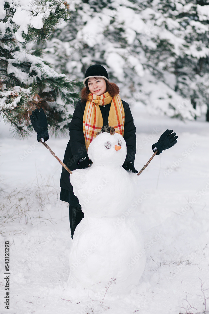 A woman made a snowman in the forest.
