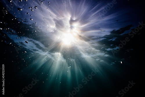 underwater view of the surface of the water, the sun and waves in blue and blue tones rays of light under water.