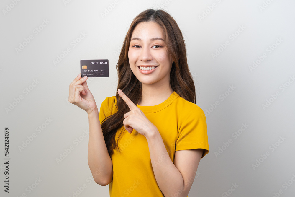 Portrait of smiling pretty brunette asian young woman, girl student in yellow casual hand holding, showing credit card for buy, payment purchase to shopping, copy space isolated white background Portrait of smiling pretty brunette asian young woman, girl student in yellow casual hand holding, showing credit card for buy, payment purchase to shopping, copy space isolated white background