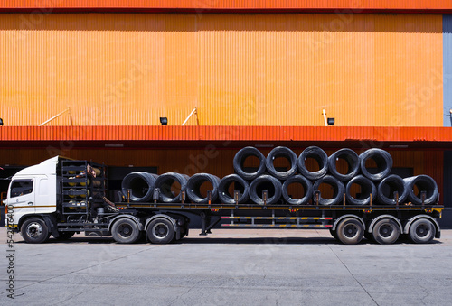 Truck load with steel coil wire in front of distribution warehouse. General cargo logistics transportation and handling. Operation activities, industrial material supply chain.