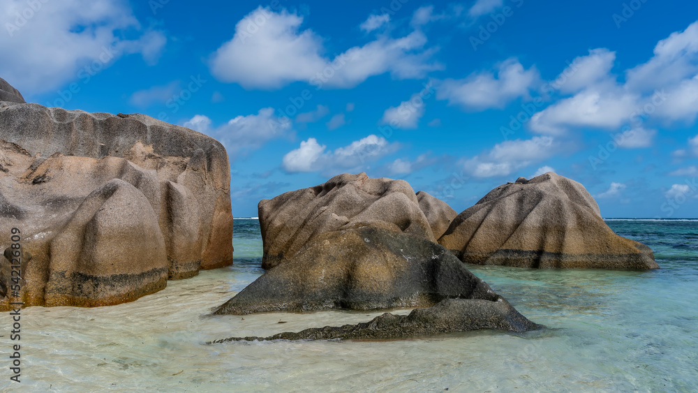 Picturesque huge granite boulders in the turquoise ocean. Bizarre outlines. Smoothed folded slopes. Blue sky with clouds. Seychelles. La Digue. Anse Source D’Argent beach Picturesque huge granite boulders in the turquoise ocean. Bizarre outlines. Smoothed folded slopes. Blue sky with clouds. Seychelles. La Digue. Anse Source D’Argent beach