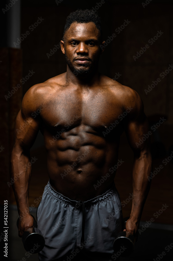 Muscular dark-skinned man doing an exercise with dumbbells. Muscular dark-skinned man doing an exercise with dumbbells.