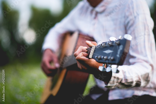 Foto The man's hand plays the acoustic guitar, plays the guitar in the garden alone, happily and loves the music