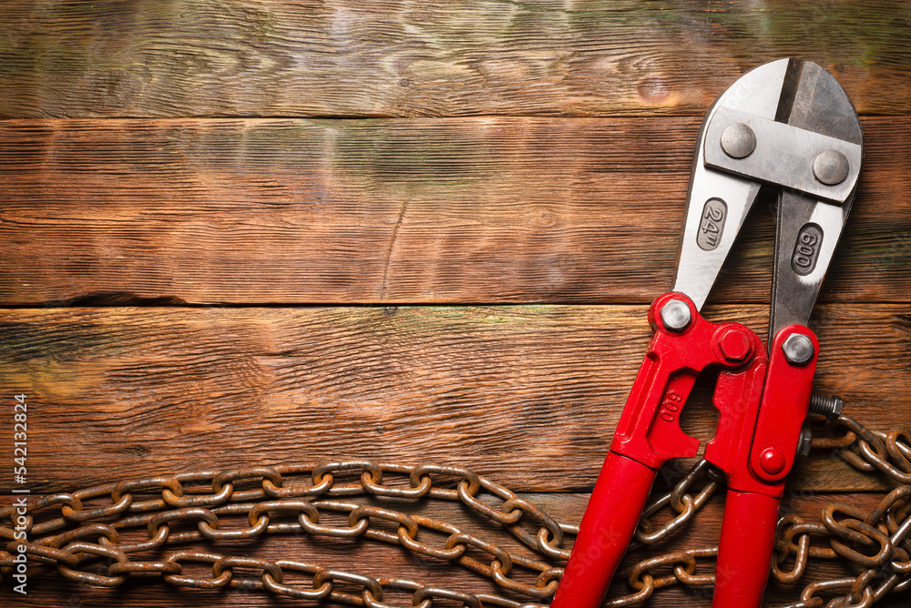 Bolt cutters rebar shears and iron chain on brown wooden workbench