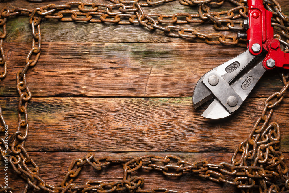 Bolt cutters rebar shears and iron chain on brown wooden workbench