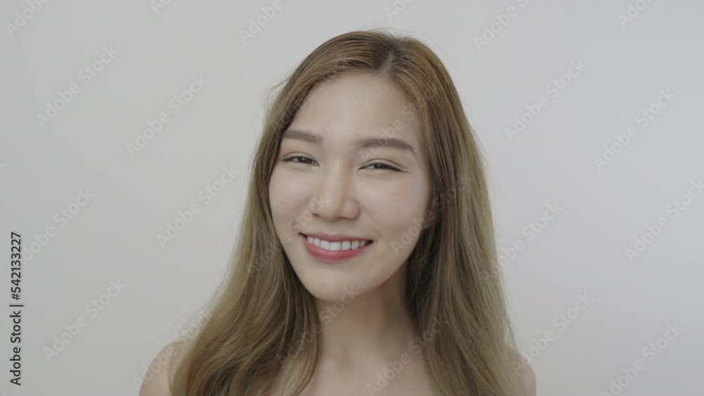 Beauty portrait. Beautiful Asian woman, natural cosmetic skincare products look at camera, smiling, healthy skin in slow motion. Beauty portrait. Beautiful Asian woman, natural cosmetic skincare products look at camera, smiling, healthy skin in slow motion.