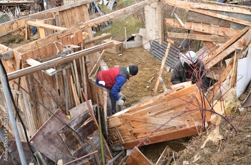 Workers disassemble and demolish an old wooden hut by hand