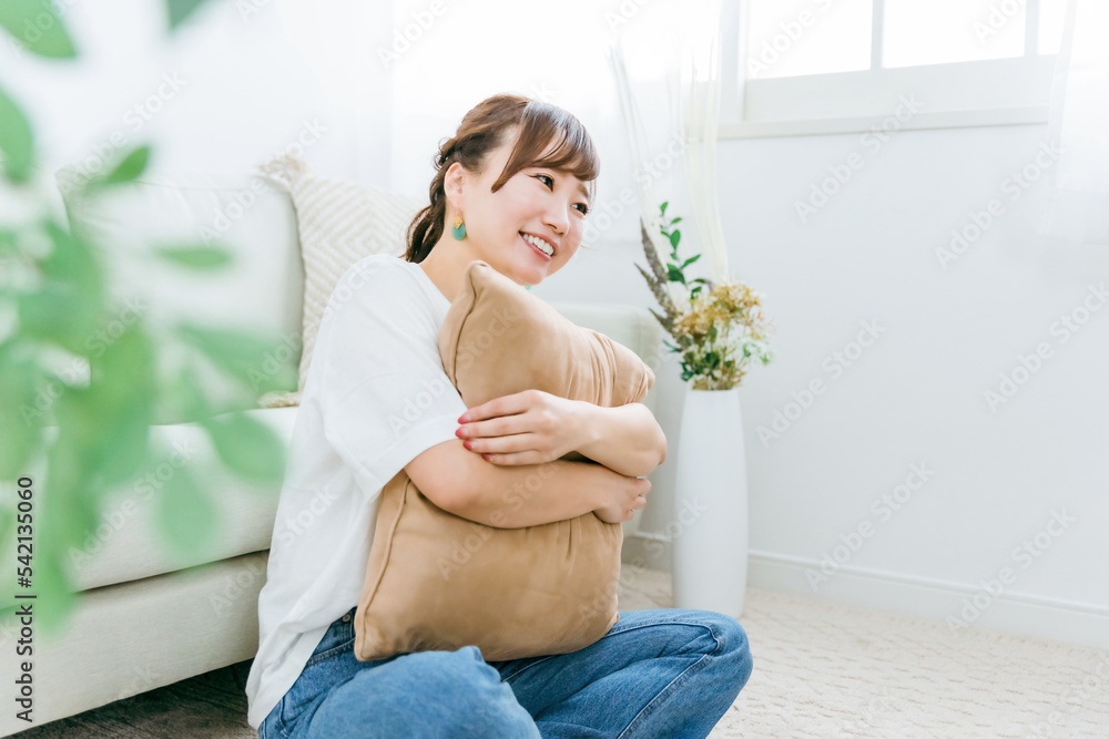 家でクッションを持つ笑顔のアジア人女性 家でクッションを持つ笑顔のアジア人女性