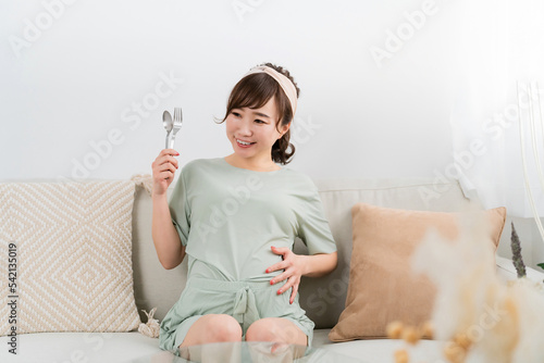 スプーンとフォークを持つ日本人の妊婦（大食い・食事）
 photo