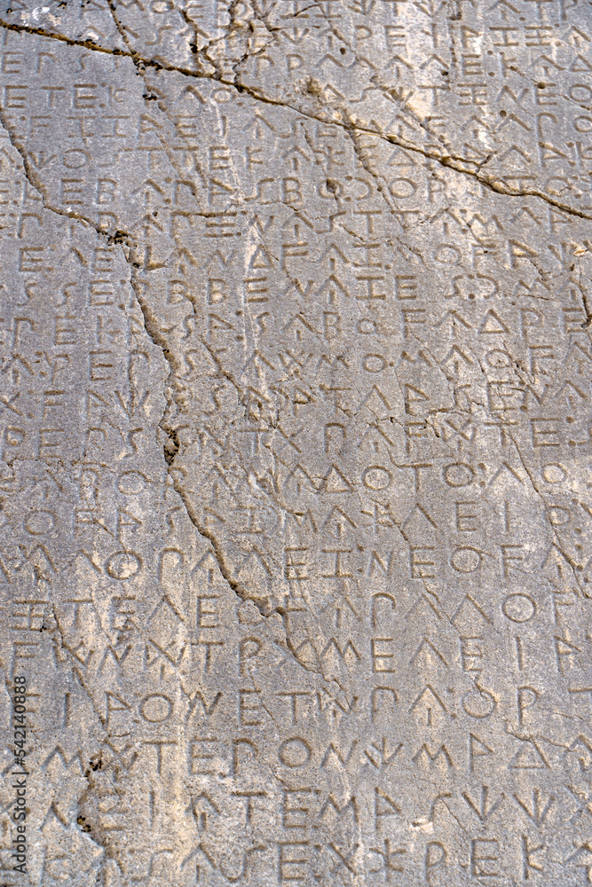 Ancient Greek antique text and inscriptions on the stone wall of the temple. Ancient Greek culture, alphabet and writing background, history concept.