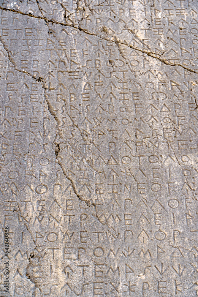 Fototapeta premium Ancient Greek antique text and inscriptions on the stone wall of the temple. Ancient Greek culture, alphabet and writing background, history concept.