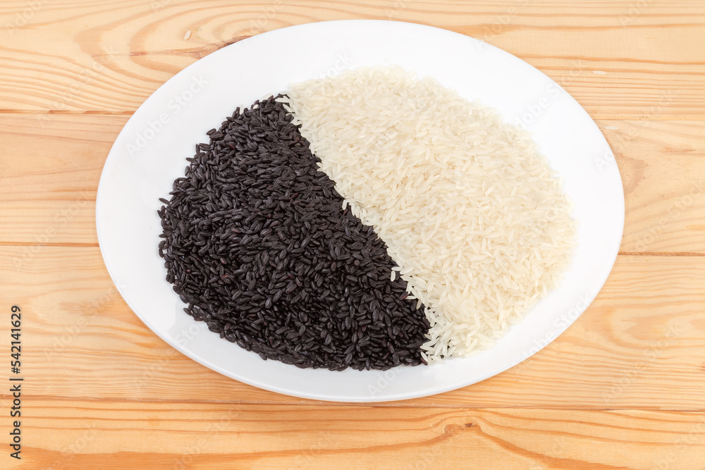 Raw black and white rice on dish on rustic table Raw black and white rice on dish on rustic table