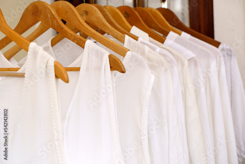Organic eco clothes on a hanger. Home-made white clothing from natural and processed fabrics, natural vegetable ingredients. Eco-friendly dresses and shirts © uladzimirzuyeu