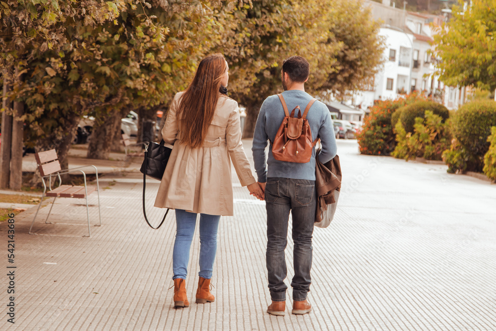 Young couple in love walking in the autumn park holding hands