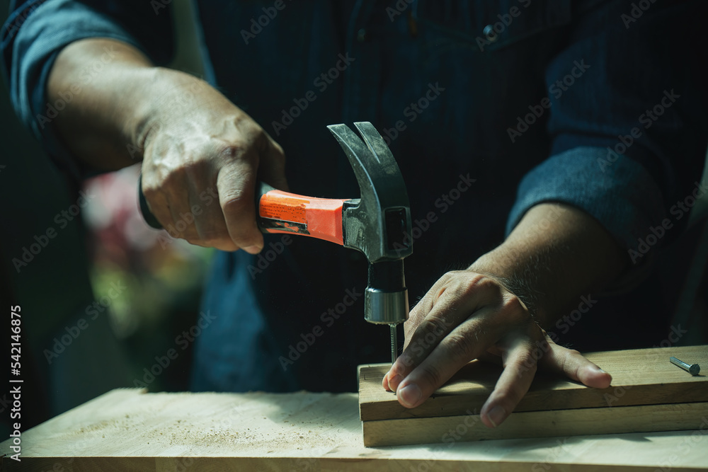 A carpenter furniture maker hammers a nail into the back of the cabinet with a hammer A carpenter furniture maker hammers a nail into the back of the cabinet with a hammer