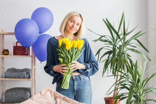 Happy adult woman hold bouquet of flowers at home