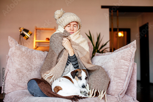 Woman warmly clothed and hat in a cold home sitting on couch