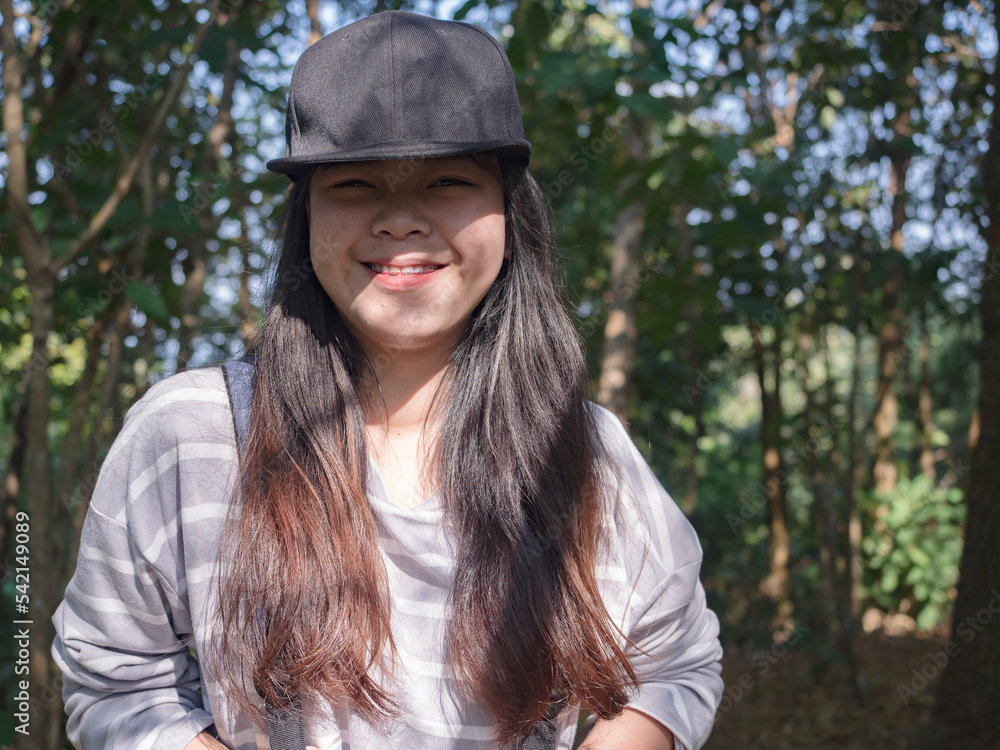Happy young Asian woman with backpack walking on path in summer forest. Happy young Asian woman with backpack walking on path in summer forest.