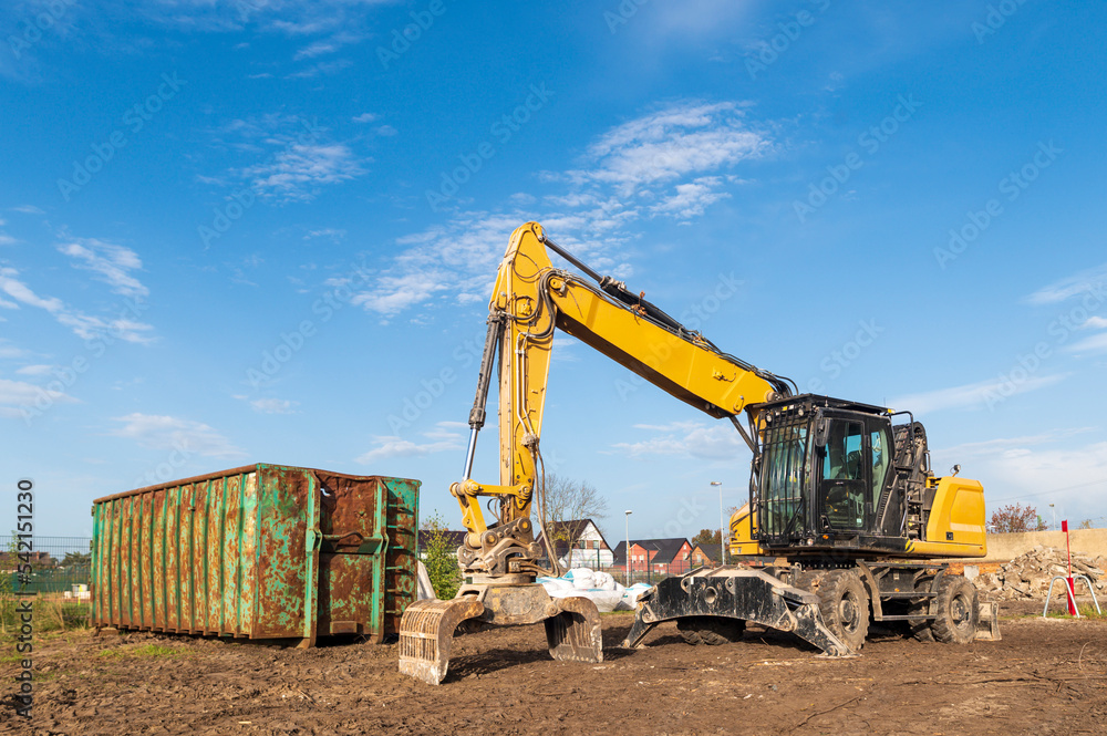 Ein Bagger steht neben einem Schuttcontainer Ein Bagger steht neben einem Schuttcontainer