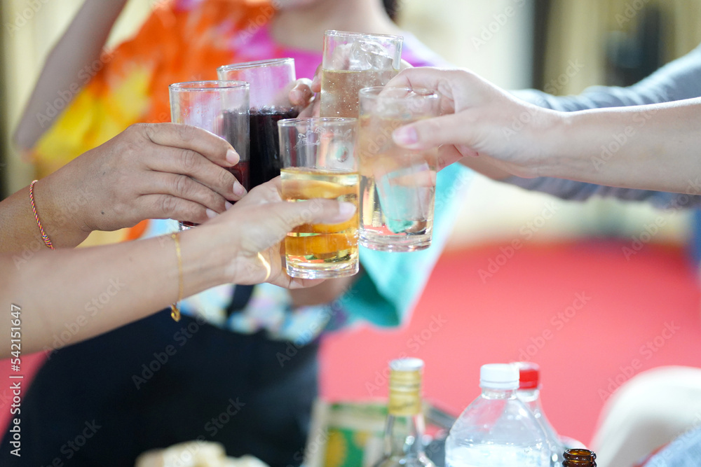 Hands clinking drinking glasses with friends at a fun and happy party.,select focus Hands clinking drinking glasses with friends at a fun and happy party.,select focus
