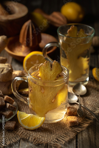 Ginger tea with lemon in a glass cup on an old wooden board.