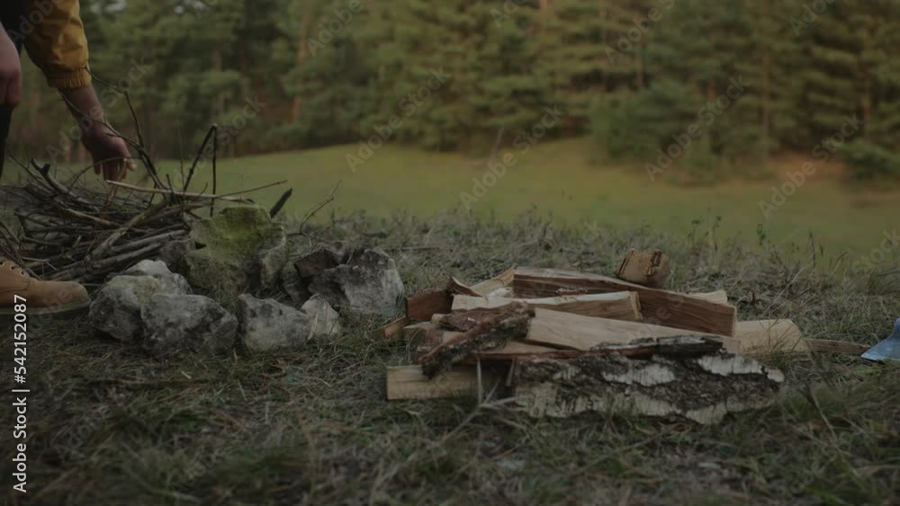 Survival in the wild. A bearded man lights a fire near a makeshift shelter made of pine branches. Survival in the wild. A bearded man lights a fire near a makeshift shelter made of pine branches.
