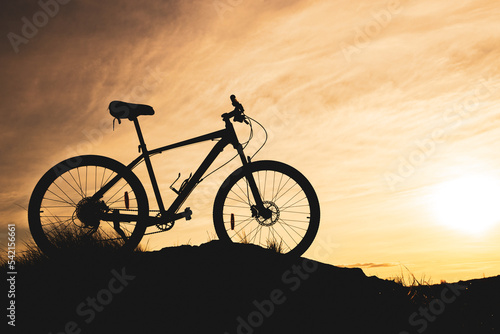 blurry clouds during sunset and a bicycle silhouette in the foreground
