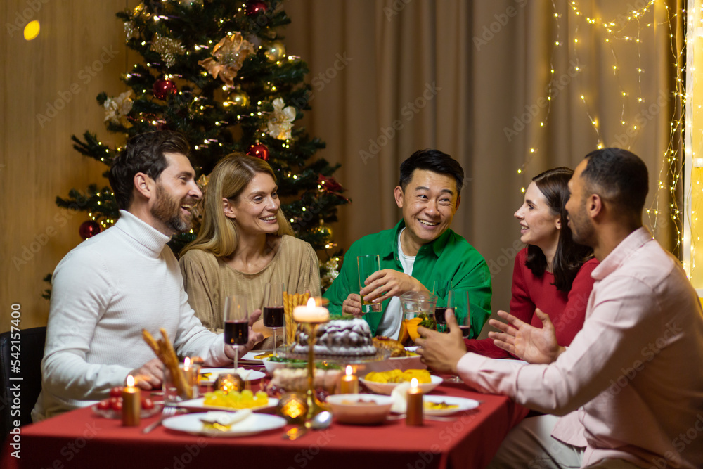 Friends celebrate Christmas eve or New Year holiday paty together sitting at the table. Feast at home group of multi ethnic festive christmas dinner. happy cheerful people. Friends celebrate Christmas eve or New Year holiday paty together sitting at the table. Feast at home group of multi ethnic festive christmas dinner. happy cheerful people.