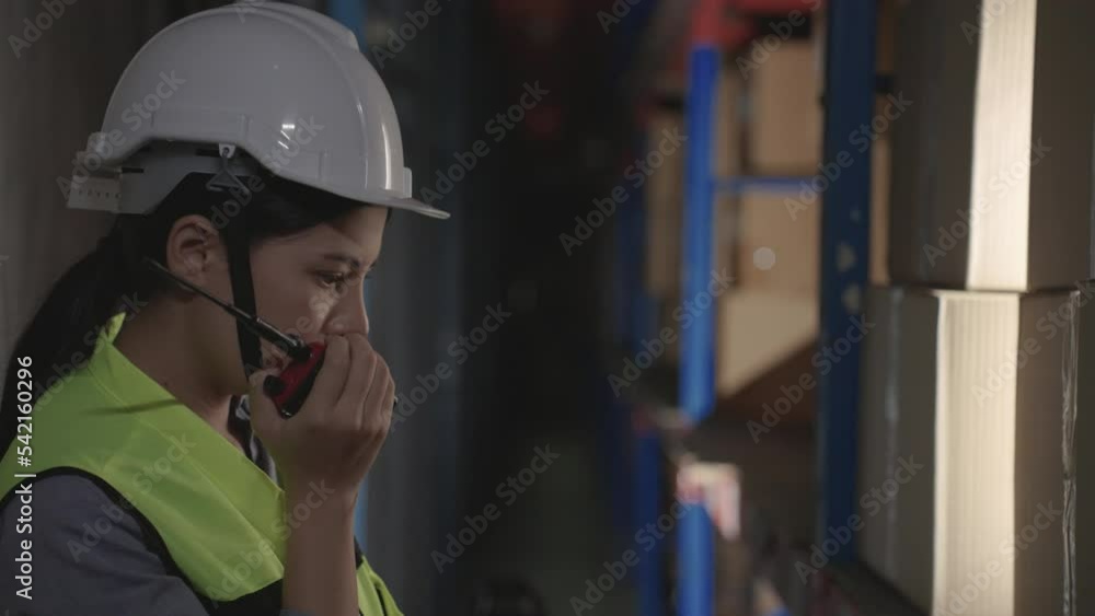 Woman manager operate in warehouses use radios walkie-talkies and tablet to inspect cartons on racks or shelves, Logistics, Import, Export, Shipping yard, Work at night. Woman manager operate in warehouses use radios walkie-talkies and tablet to inspect cartons on racks or shelves, Logistics, Import, Export, Shipping yard, Work at night.