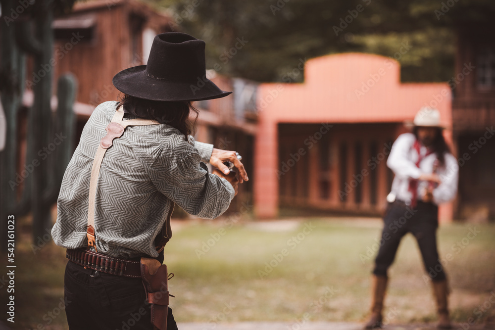Backside view of cowboy while standing gun prepares on gunfight in cowboys village is cowboy western lifestyle concept.	 - obrazy, fototapety, plakaty 