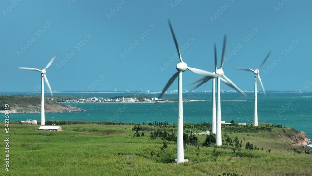 Aerial view of giant wind turbines standing in the green field by the beach in a seaside park , Penghu County, Taiwan. Aerial view of giant wind turbines standing in the green field by the beach in a seaside park , Penghu County, Taiwan.