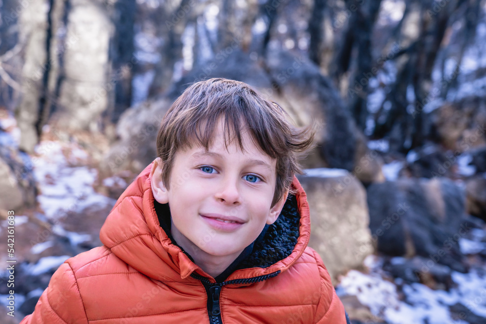 Portrait of a boy (8 years old, white, Caucasian) against a blurred background of a winter mountain forest Portrait of a boy (8 years old, white, Caucasian) against a blurred background of a winter mountain forest