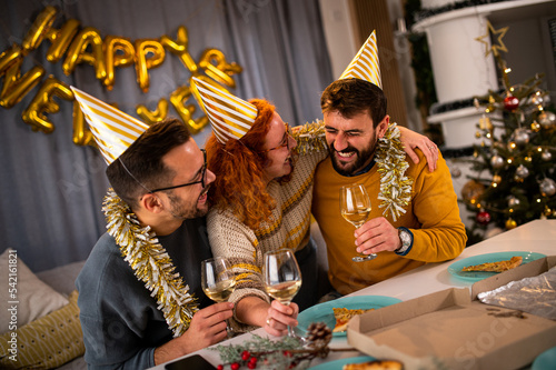 Young people looking at the camera smiling and laughing at the new year's party drinking wine and champagne.