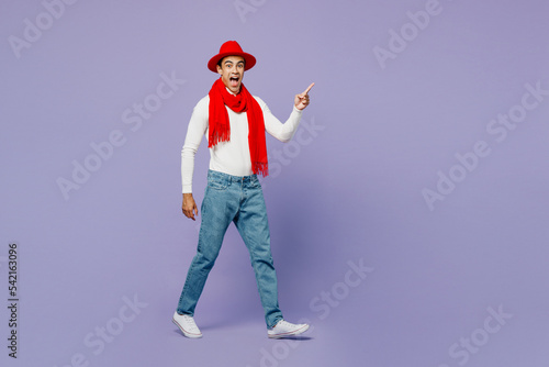 Full body side view young middle eastern man wear white turtleneck red hat scarf point index finger aside on workspace area isolated on plain pastel light purple background People lifestyle concept © ViDi Studio