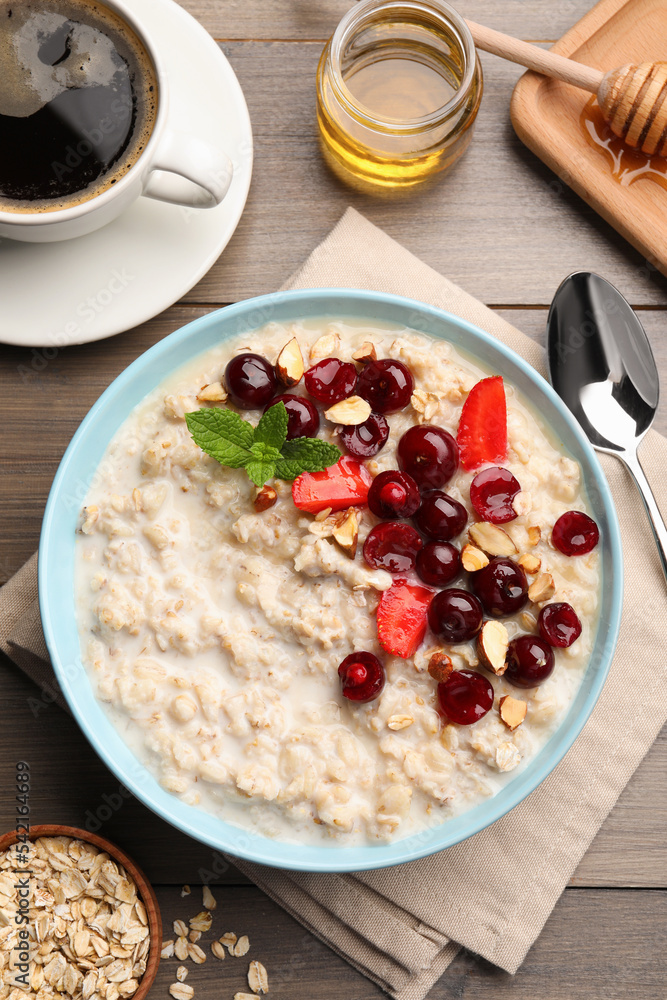 Bowl of oatmeal porridge served with berries on wooden table, flat lay Bowl of oatmeal porridge served with berries on wooden table, flat lay
