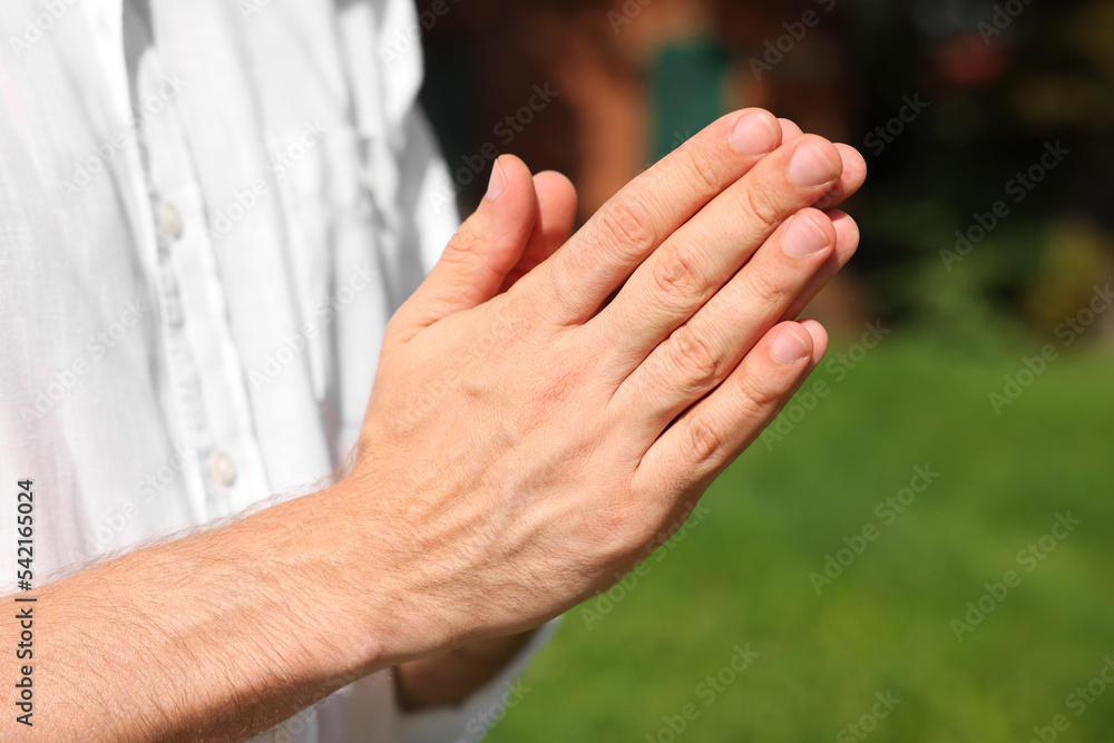 Man praying outdoors on sunny day, closeup Man praying outdoors on sunny day, closeup