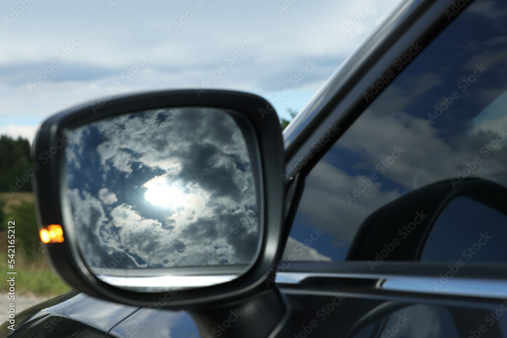 New black modern car outdoors, closeup of side rear view mirror