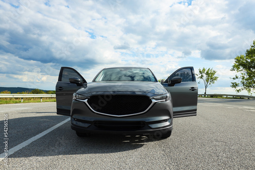 New black modern car with open doors on asphalt road