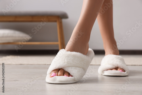 Woman wearing white soft slippers indoors, closeup. Space for text photo