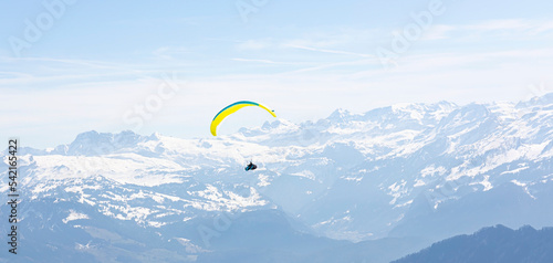 Paraglider Fly in the Mountains as snow apls mountain background