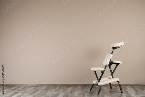 Modern massage chair near beige wall indoors, space for text. Medical equipment