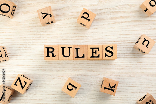 Word Rules made of cubes with letters on light wooden table, flat lay photo