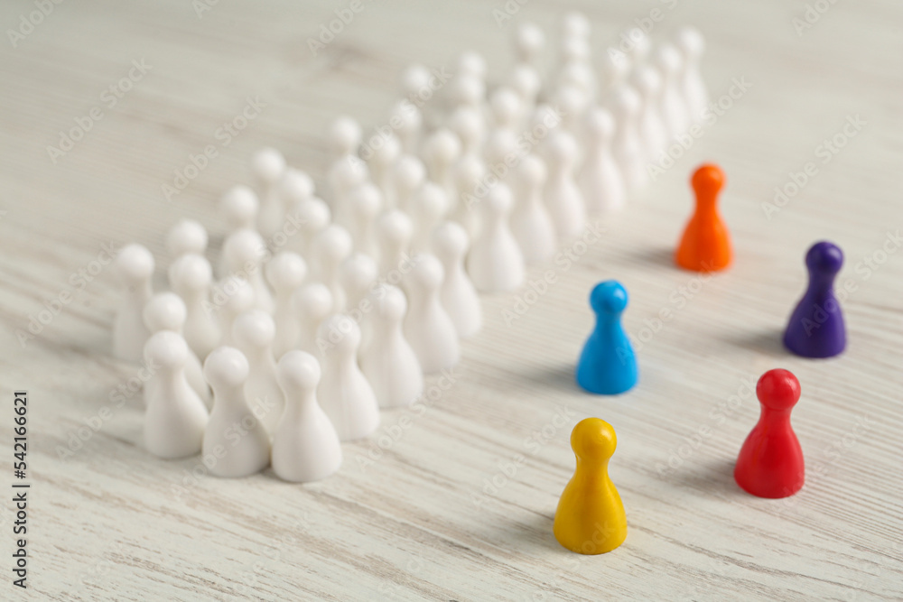 Colorful pawns on white wooden table. Social inclusion concept Colorful pawns on white wooden table. Social inclusion concept