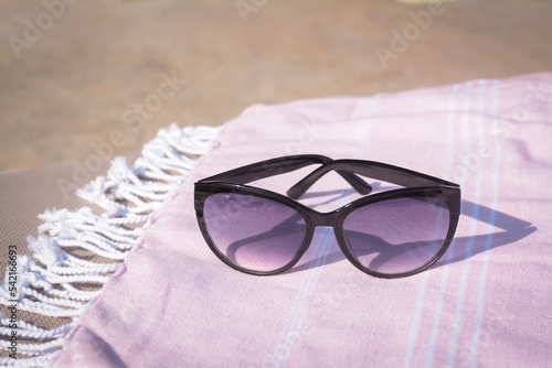 Stylish sunglasses on blanket outdoors  closeup. Beach accessories