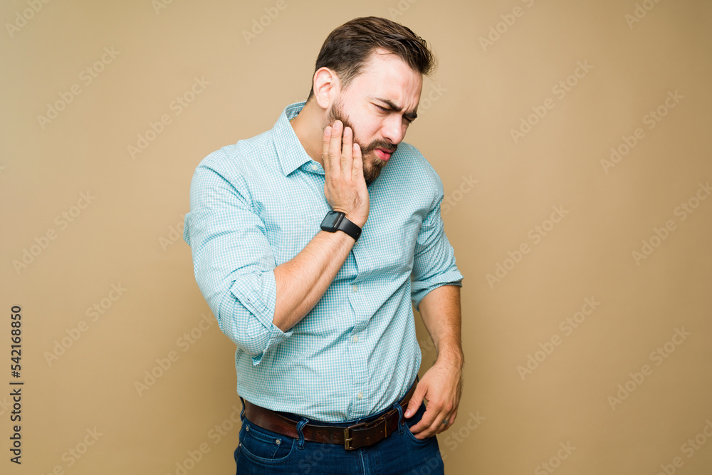 Stressed man touching his face suffering from toothache Stressed man touching his face suffering from toothache